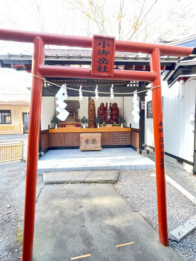 新屋山神社の境内にある小御岳社。赤い鳥居の奥に祠と福の神像が並ぶ
