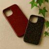 津軽塗のiPhoneケース2種（唐塗の赤と呂の黒）。ベージュの布の上に平行に並び、右上にアイビーの葉を添えた商品写真。