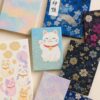 パステルカラーの御朱印帳と、可愛らしい猫のイラストをあしらった御朱印帳が並ぶ華やかなディスプレイ
