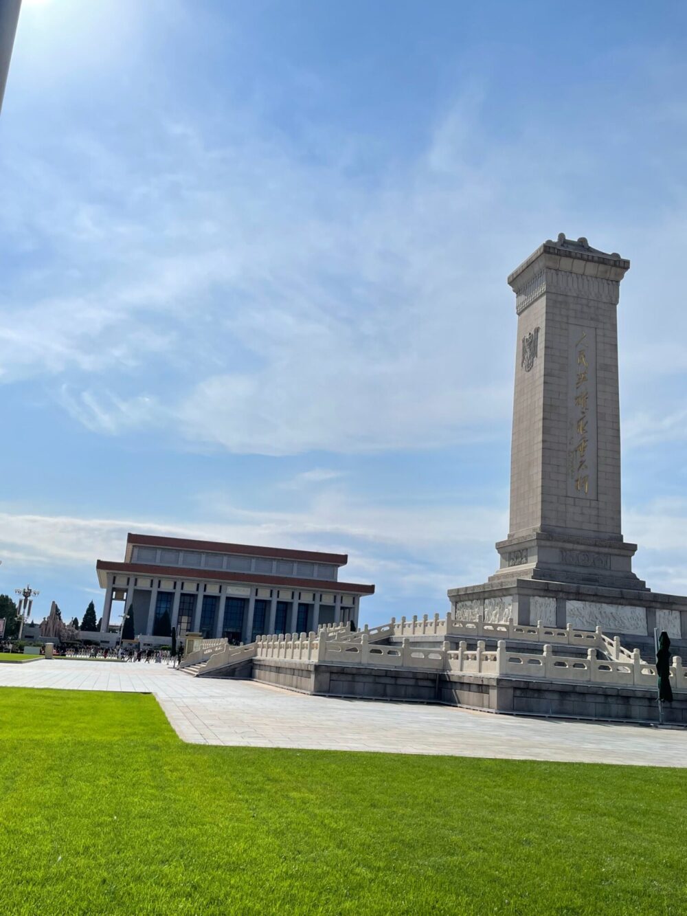 人民英雄記念碑の石塔と、その奥に広がる毛主席紀念堂。晴れ渡る空と芝生が広場の広大さを際立たせている。