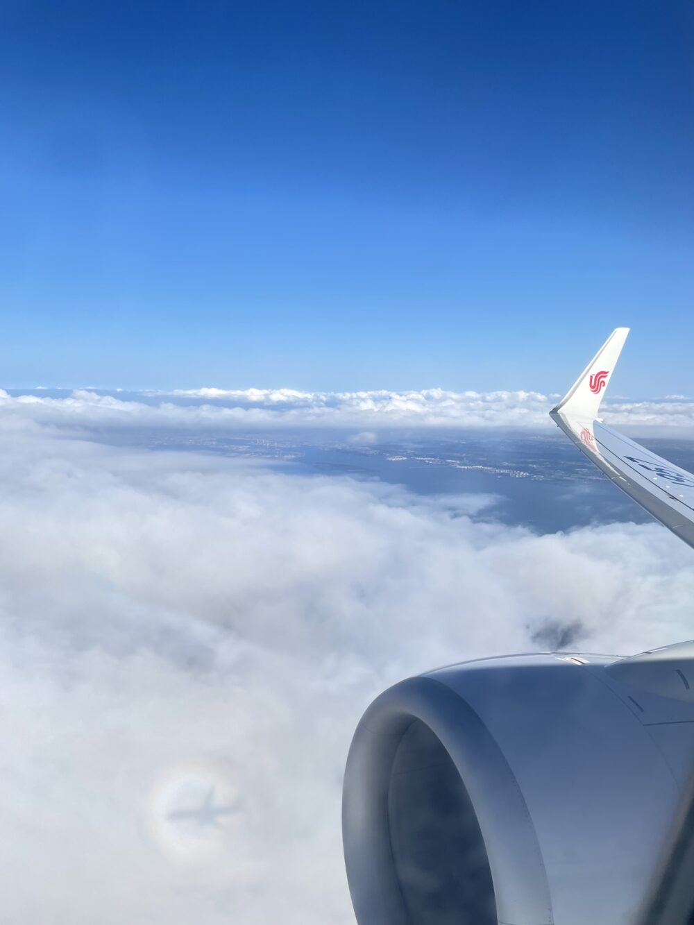 中国国際航空の機体から見た雲海と青空。雲に飛行機の影が映るブロッケン現象が見える。