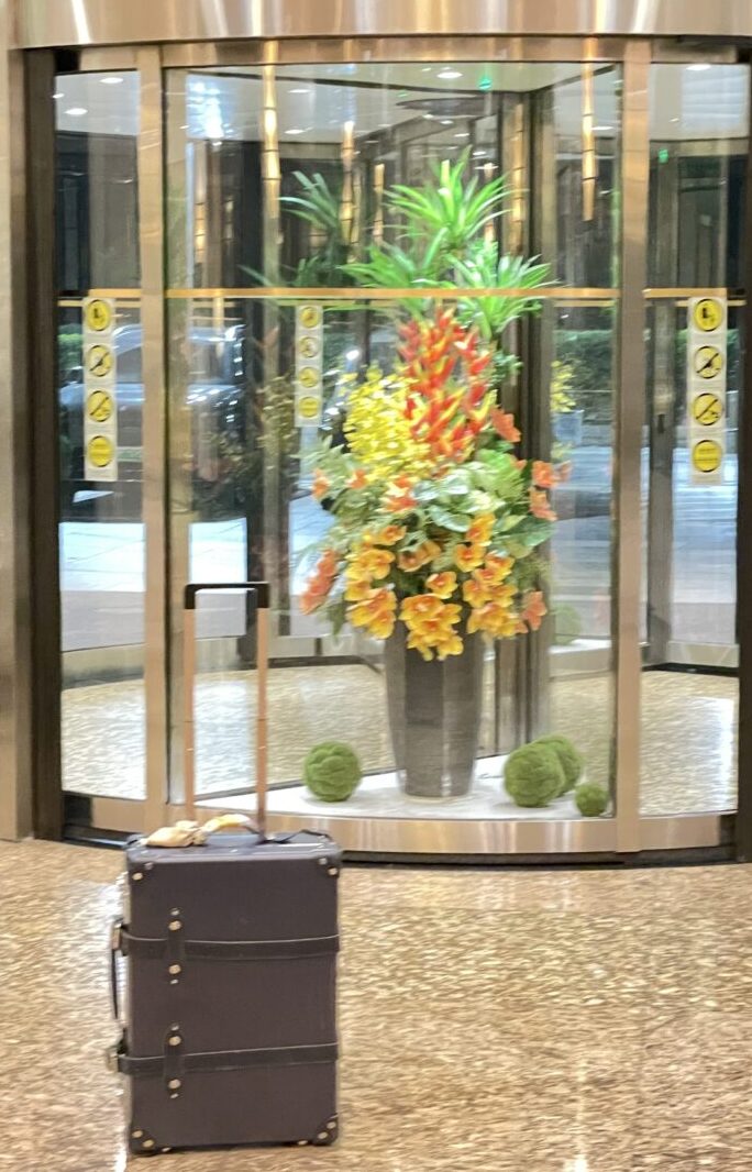 ホテルの回転扉の前に置かれたグローブ・トロッターのスーツケース。