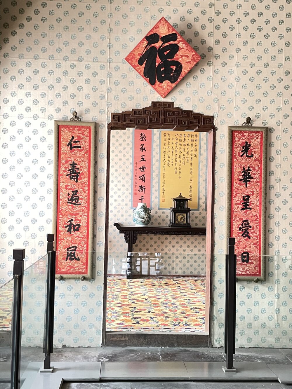紫禁城・寿康宮の室内装飾。菱形に掲げられた「福」の字と左右の対聯、奥に供棚と時計が見える展示空間