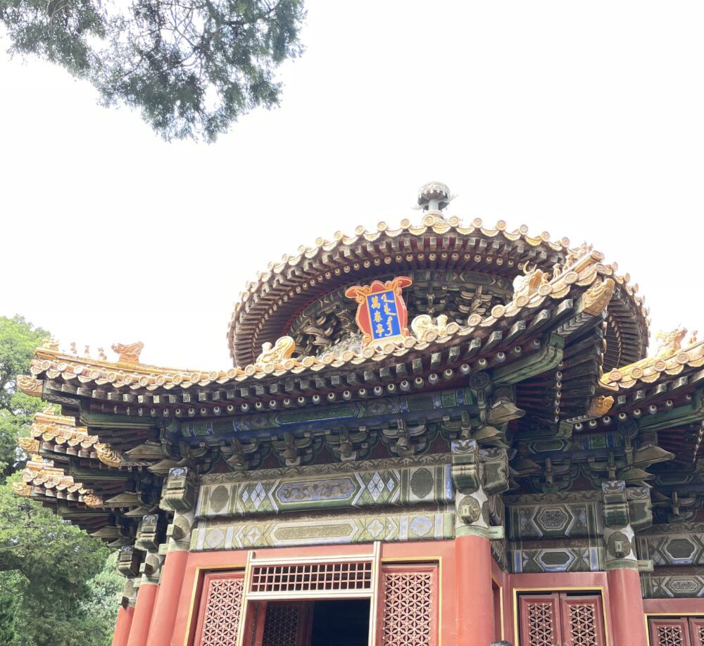 紫禁城・御花園にある「万春亭」の外観。丸い屋根に金色の飾り瓦が連なり、重厚な斗拱と色鮮やかな彩色が施された優美な東亭。