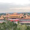 景山公園の展望エリアから望む故宮・紫禁城の全景。北門（神武門）を正面に、黄金色の宮殿群が奥へと連なり、北京の街並みまで見渡せる雄大な風景。