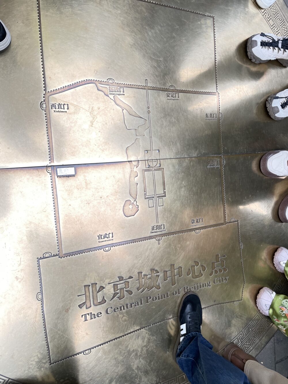 北京の地理的中心点を示す金属製の地図パネル。東西南北の城門と故宮の位置関係が刻まれている。