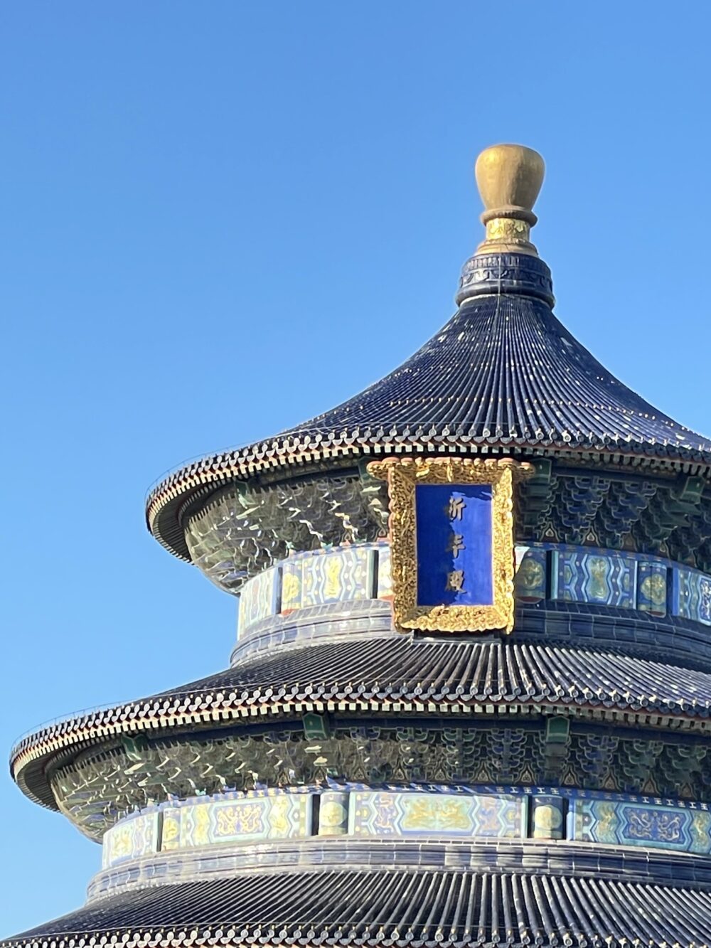北京・天壇公園の祈年殿の三層青瓦屋根と扁額。円形構造と金色の宝頂が特徴の明清時代の祭天建築