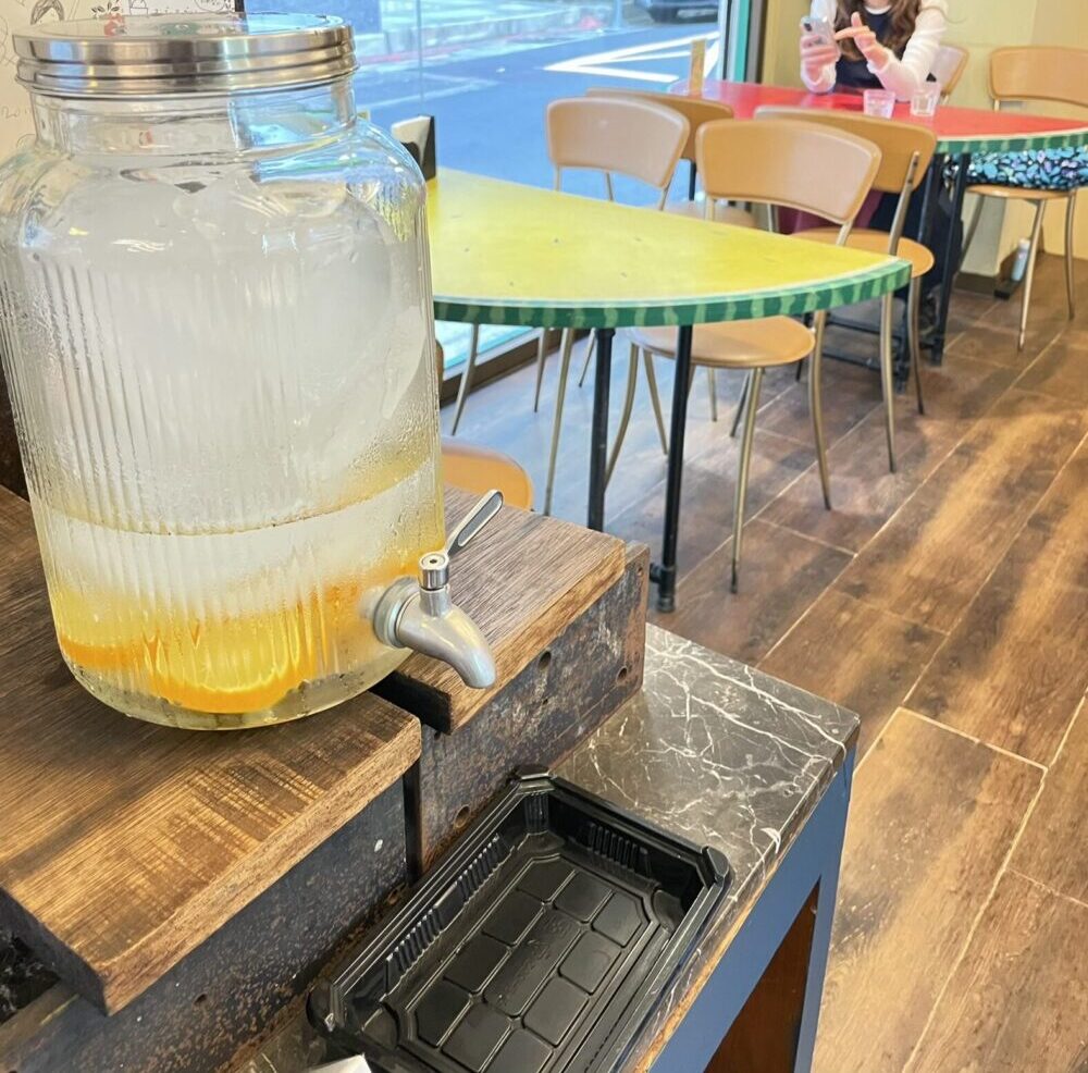 陳記百果園の店内セルフウォーター｜柑橘入りのフルーツウォーターとレトロなテーブル（台北）