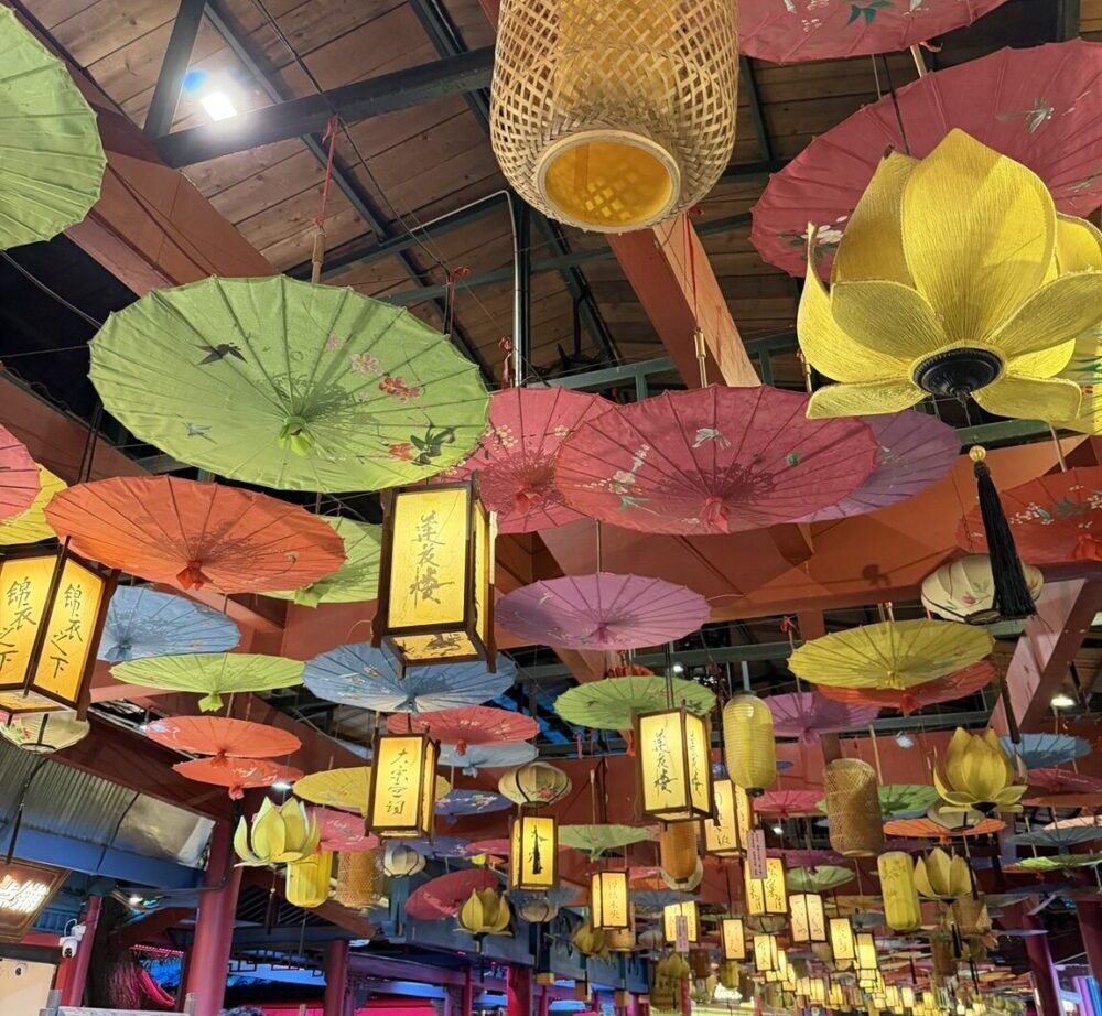 横店影視城・清明上河図の装飾。色とりどりの和傘や提灯、蓮の花灯籠が天井いっぱいに飾られた華やかな空間