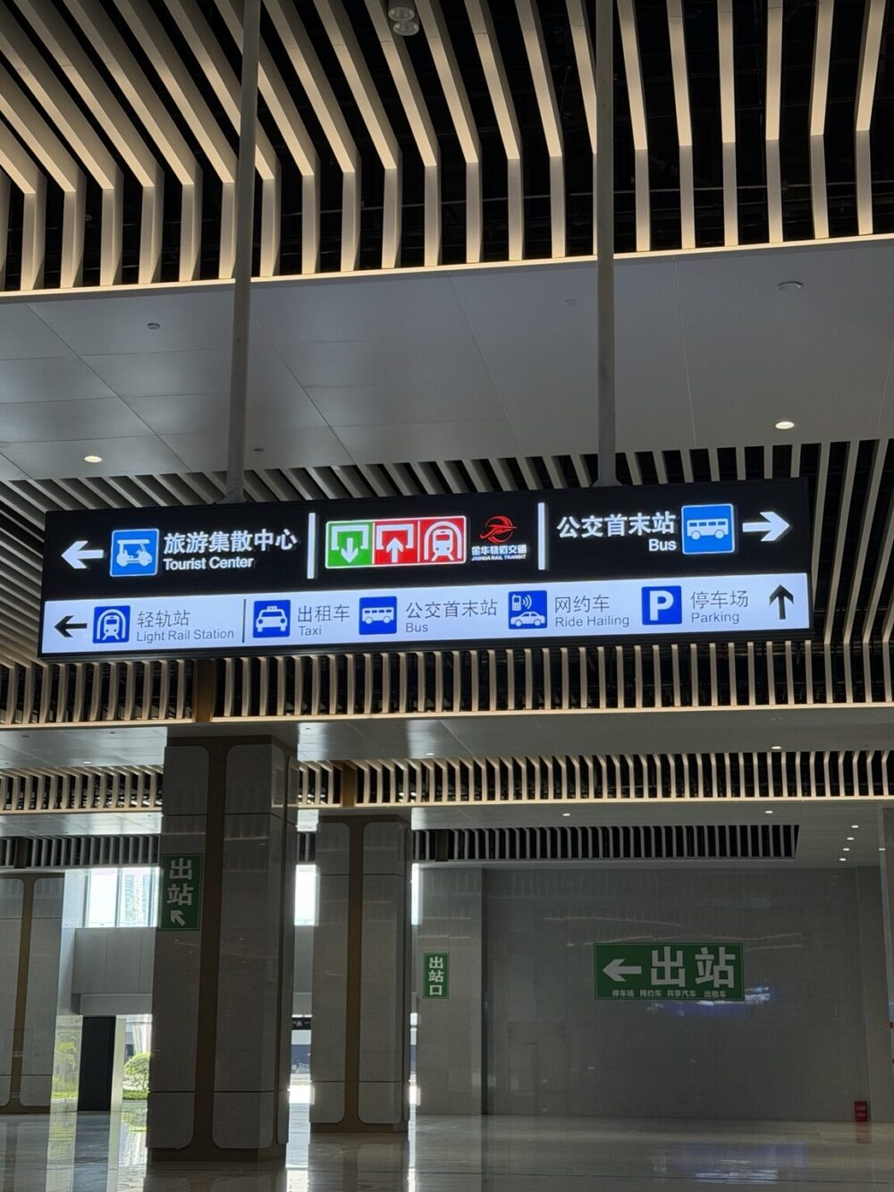 横店駅構内の案内表示。DiDi乗り場（Ride Hailing）やタクシー、バスの方向が英語併記で表示されている